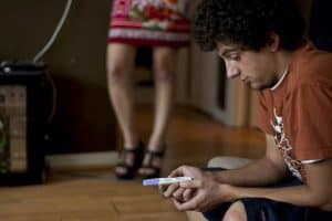 man holding pregnancy test with woman in background