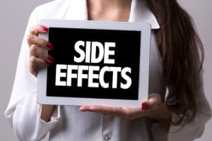 Woman holding a "SIDE EFFECTS" sign