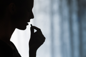 A woman's silhouette showing her taking in a medicine capsule