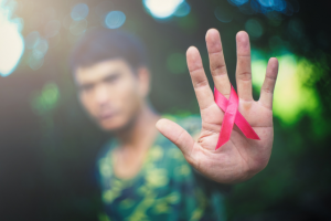 Man showing a red HIV ribbon on the palm of his hand